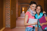 Two cheerful students posing in hallway