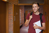 Handsome smiling student standing in hallway
