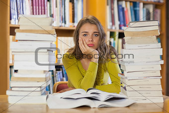 Exhausted pretty student studying between piles of books