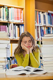 Tired beautiful student studying between piles of books with closed eyes
