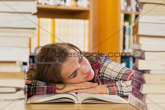 Tired pretty student resting head on table between piles of books