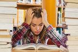Irritated pretty student studying between piles of books