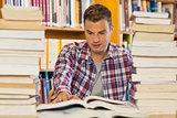 Handsome student studying between piles of books