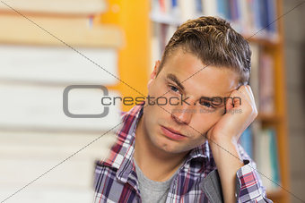 Exhausted handsome student studying between piles of books