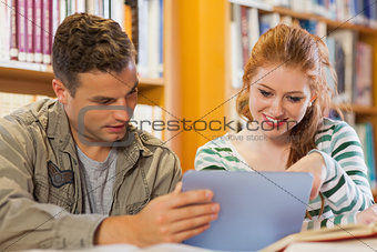 Two cheerful students studying together using tablet