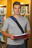 Handsome smiling student holding folder and notebooks