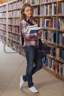 Pretty smiling student looking at camera holding books