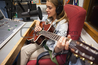Focused pretty singer recording and playing guitar