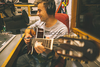 Smiling handsome singer recording and playing guitar