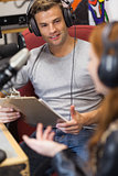Attractive radio host interviewing a guest holding clipboard