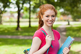 Gorgeous smiling student holding notebooks looking at camera