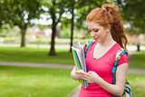 Gorgeous smiling student holding notebooks texting