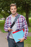 Handsome smiling student standing and texting