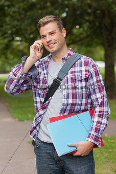 Handsome smiling student standing and phoning