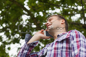 Handsome laughing student standing and phoning