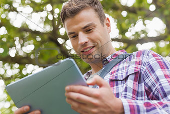 Handsome happy student using tablet