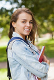 Pretty gleeful student holding folder and notebook