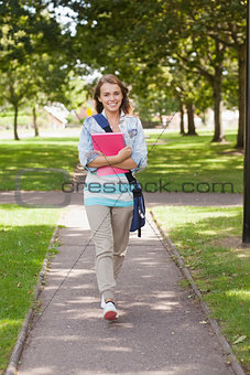Pretty happy student carrying notebook walking