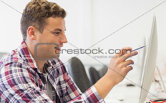 Handsome smiling student pointing at computer