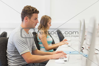 Two serious students working on computer individually