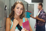 Smiling pretty student standing next to locker
