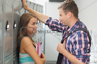 Two smiling students leaning against locker flirting