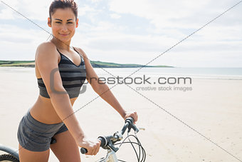 Young woman posing with her bike on beach
