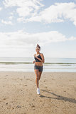Sporty brunette woman jogging on the beach