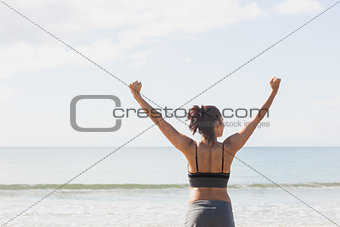 Lovely slender woman stretching her arms on the beach
