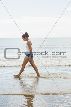 Thoughtful slim woman walking on the beach
