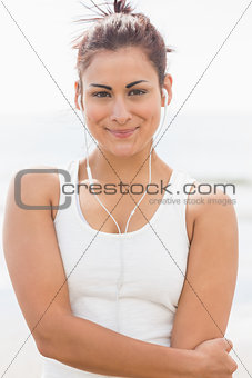 Beautiful smiling woman listening to music at beach