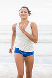 Sporty woman jogging on beach towards camera