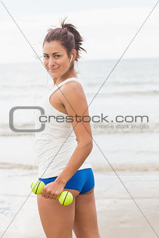Pretty smiling sporty woman holding dumbbells smiling at camera