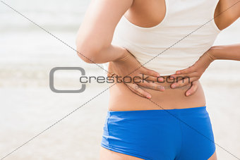 Mid section of sporty woman holding her back