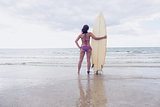 Woman in bikini with surfboard on beach