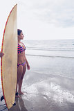 Woman in bikini with surfboard on beach