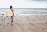 Calm woman carrying surfboard on the beach