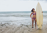 Full length of a bikini woman holding surfboard at beach