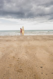 Calm woman in bikini with surfboard on beach