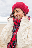 Cute smiling woman in warm clothing looking away at beach