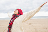Woman in warm clothing stretching her arms at beach