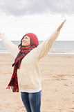 Woman in warm clothing stretching her arms at beach