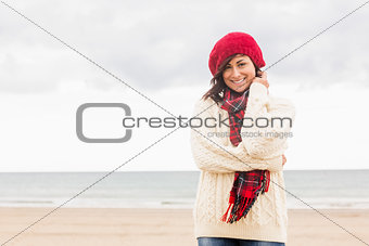 Cute smiling woman in stylish warm clothing at beach