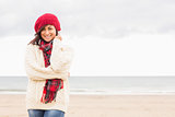 Cute smiling woman in stylish warm clothing at beach