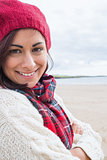 Woman in knitted hat and pullover smiling at beach
