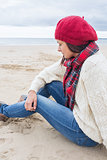 Woman in stylish warm clothing sitting at the beach