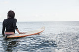 Rear view of a woman with surfboard in the water