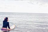 Rear view of a woman sitting on surfboard in water