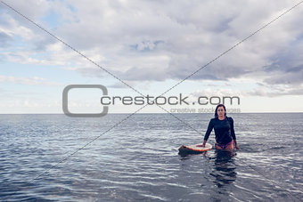 Portrait of a beautiful young woman with surfboard in water