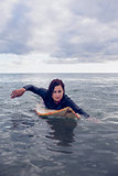Woman swimming over surfboard in water